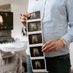 A person holding ultrasound images in a medical clinic, showcasing pregnancy monitoring.