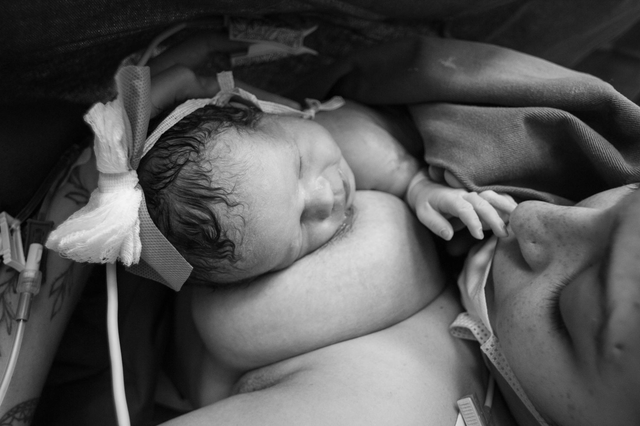 Tender black and white photo capturing the intimate bond between mother and newborn during skin-to-skin contact.